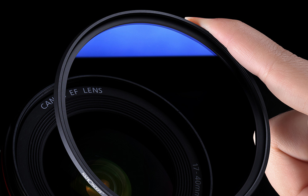Tenant un filtre optique bleu en main, objectif de caméra en arrière-plan