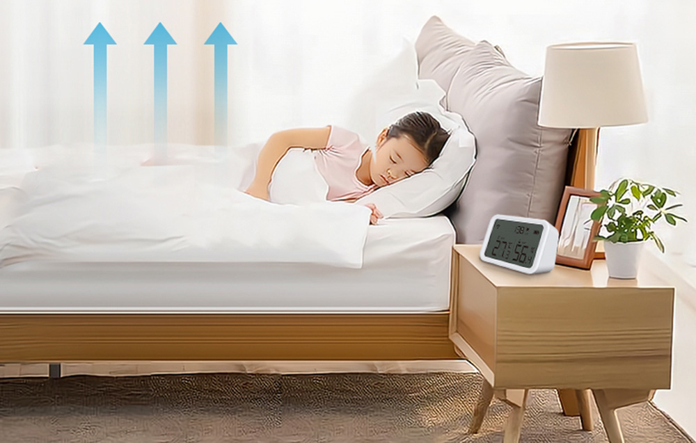 Capteur de température et d'humidité NEO NAS-TH02W avec affichage Zigbee TUYA posé sur une table de chevet près d'un lit où dort un enfant.