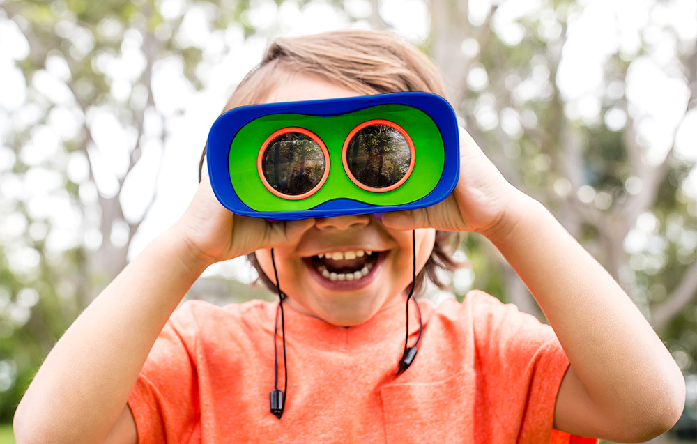 Garçon utilisant les jumelles GeoSafari Learning Resources EI-5260 dans le jardin