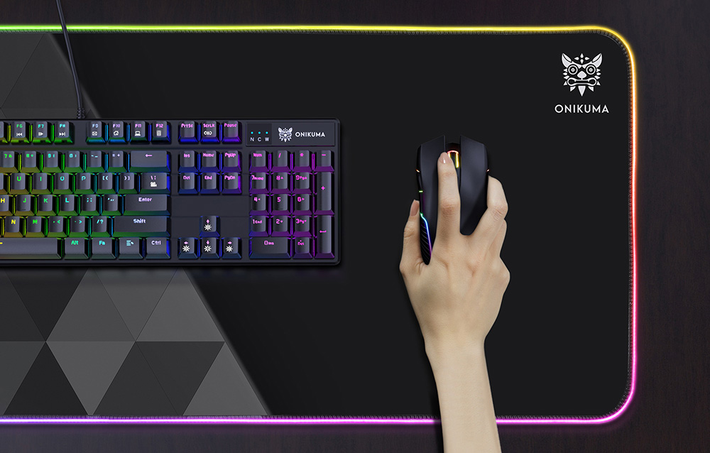 Tapis de jeu Onikuma MP006 en utilisation sur un bureau. Sur le tapis, un clavier et une souris, manipulée par quelqu'un.