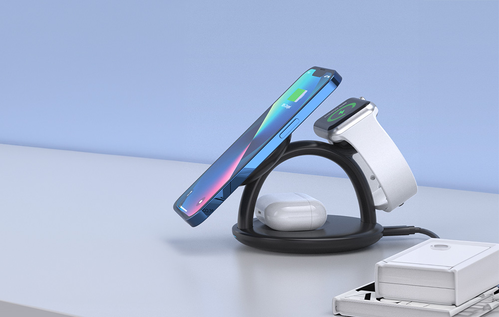 smartphone, montre connectée et écouteurs TWS connectés au chargeur inductif reposant sur une table claire, à droite des livres